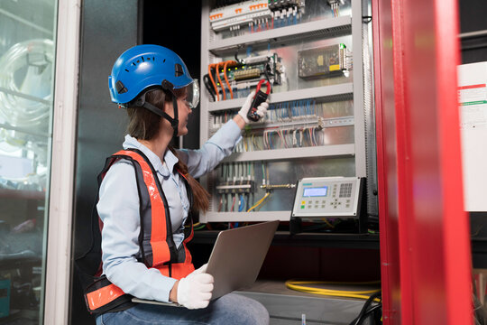 Female electrician worker checking, repair, maintenance operation electric system on electrical circuit board in factory. Woman electrician engineer working with operation electric system in workshop