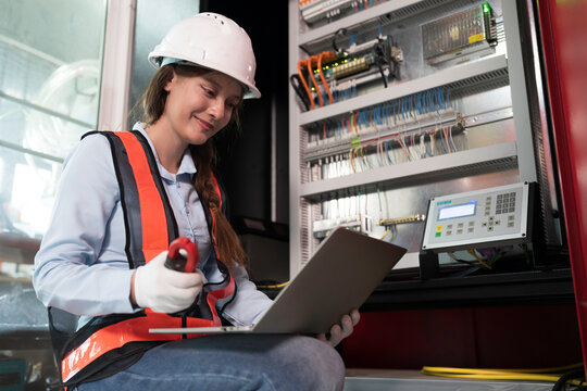 Female electrician worker checking, repair, maintenance operation electric system on electrical circuit board in factory. Woman electrician engineer working with operation electric system in workshop