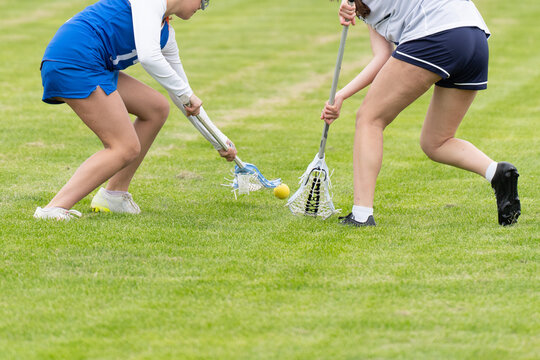 Two Lacrosse Players Competing for Ball on Grass Field
