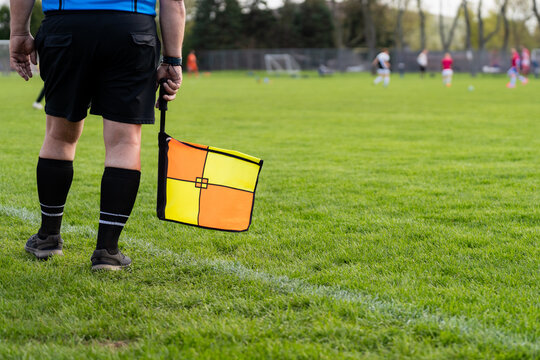 Soccer Referee Holding Offside Flag on Grass Sideline with Copy Space