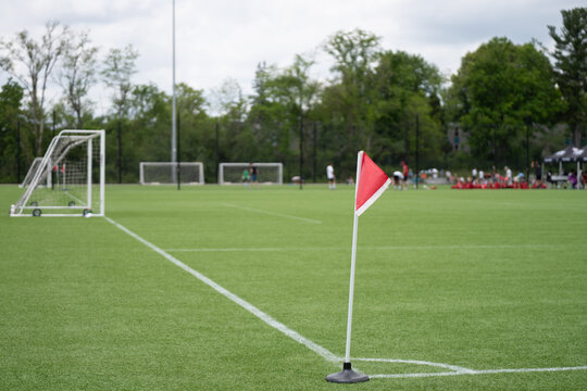 Red Corner Flag on Soccer Field with Goals and Players