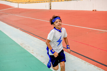 Obraz premium Child in superhero costume running on a track, smiling energetically.