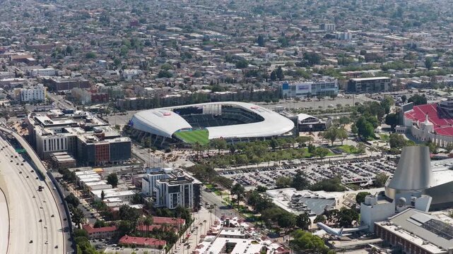 High altitude survey of Exposition Park in Los Angeles with BMO Stadium, Interstate 110 freeway, urban development, sprawling residential neighborhoods