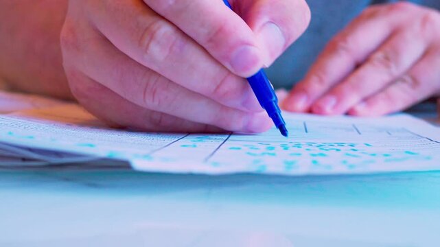 Hand filling out a paper document with a marker on a table. Close-up, shallow DoF, natural window light. Business planning.Paper work.