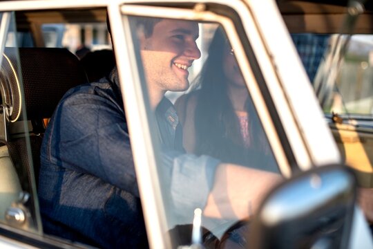 Smiling couple driving vintage car.