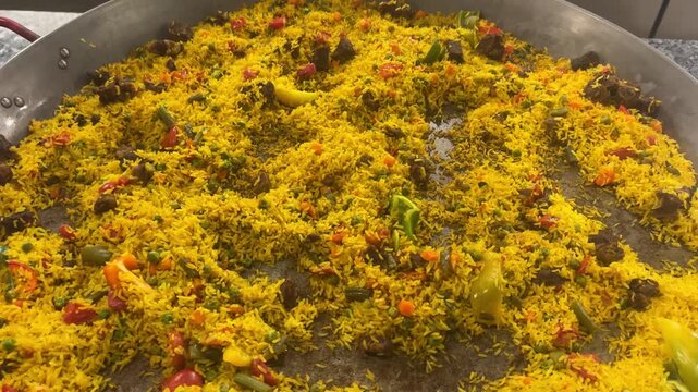 Chicken and vegetable pilaf on a large skillet, spiced rice, tender meat, colorful, hearty buffet meal.