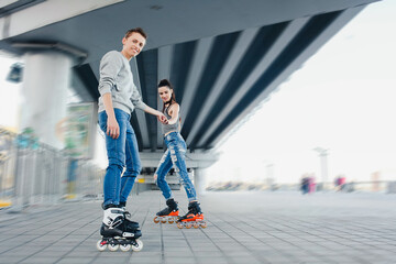 Obraz premium Young friends rollerblading under a city bridge
