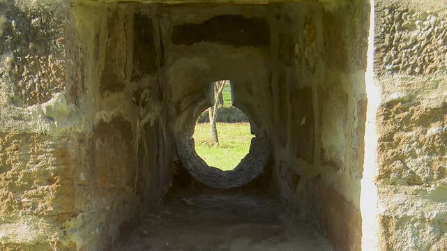View through a circular stone gun port in a medieval wall hole castle fortress