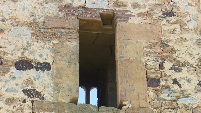 Narrow stone loophole window in an old medieval castle stone fortification wall