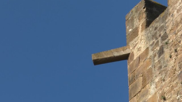 Stone gargoyle spout protruding from an ancient medieval castle fortress wall