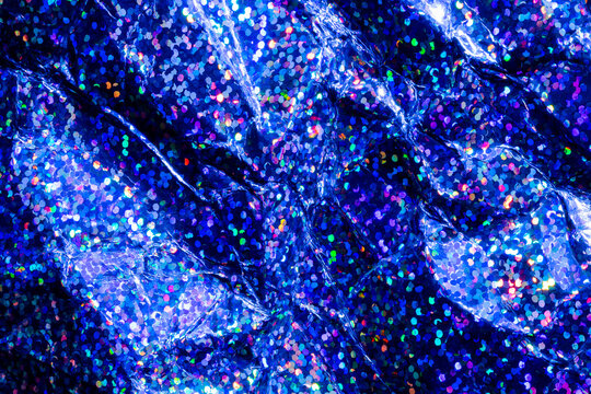 Blue holographic glitter texture with sparkling bokeh and crumpled metallic foil background