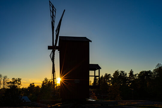 Golden sunset over historical wooden windmill with dramatic sunstar