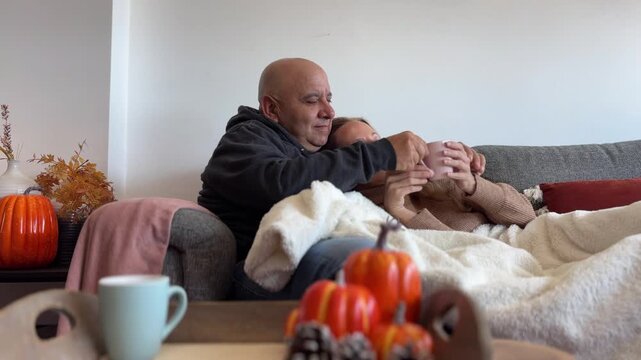 Pareja relajada con manta y caf&eacute; entre decoraci&oacute;n oto&ntilde;al