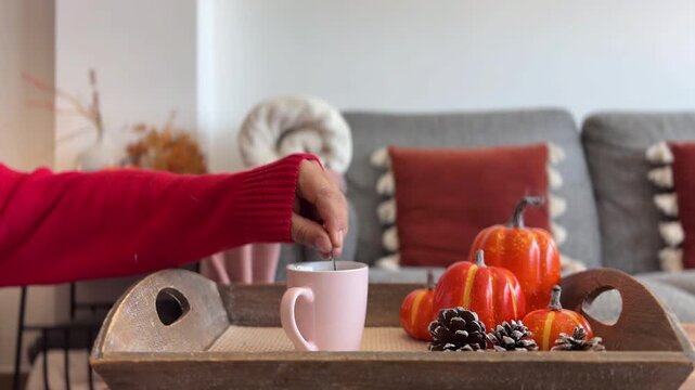 Mano removiendo caf&eacute; en bandeja con decoraci&oacute;n oto&ntilde;al