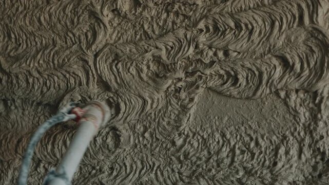 Applying plaster mortar to wall with spray machine