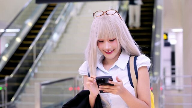 Young woman smartphone shopping mall escalator blonde hair smiling casual clothing glasses technology indoor urban communication lifestyle happiness modern leisure portrait people fashion accessory