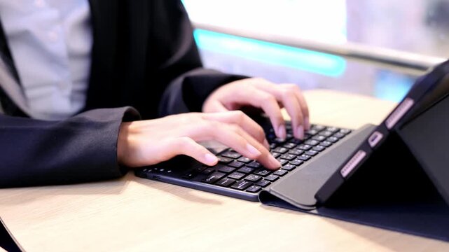 Person typing on keyboard and tablet with hands at business desk using modern technology for communication and work in professional office environment closeup focus on digital input device