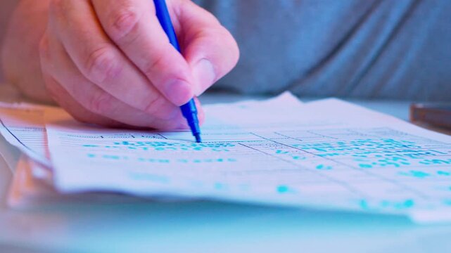 Modern business. Close-up of a hand filling out a paper document with a marker on a table.Cinematic macro shot of paper work.