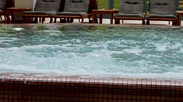 Close-up bubbling water in spa jacuzzi hot tub, luxury wellness spa, relaxing hydrotherapy, abstract water texture, 4K video footage, serene wellness background