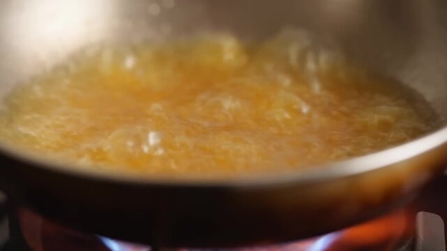 Simmering golden mixture in pan on flame: culinary heat and motion captured at high resolution