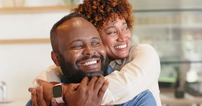 African American couple hugging, woman wrapping arms around man, sharing love in kitchen smartwatch