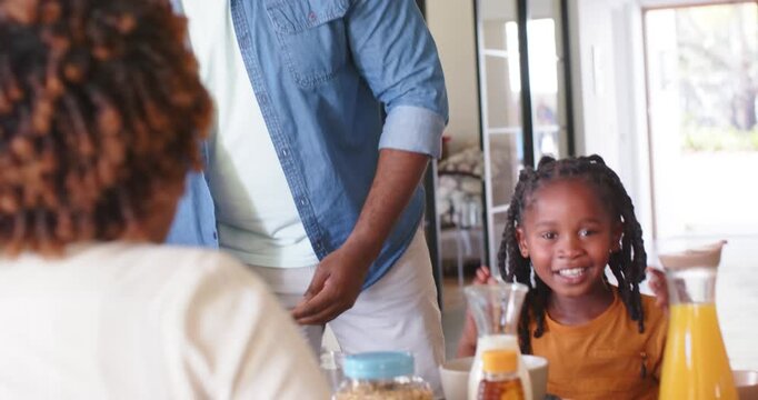 Family father entering carrying plate of red boxes, offering to girl at table, child clapping