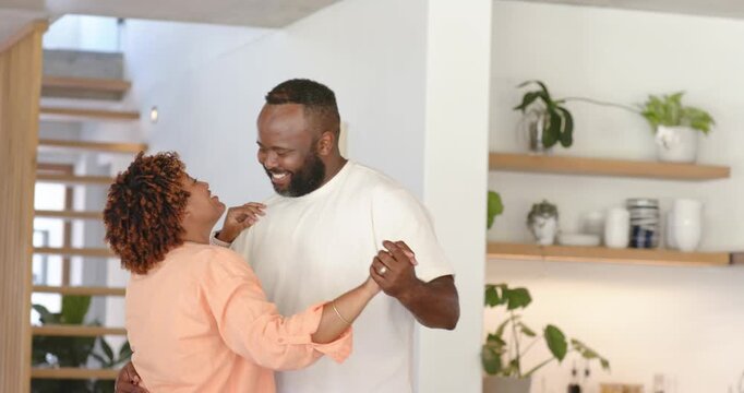 African American couple, man placing arm at waist, swaying, laughing, warmly showing ring at home