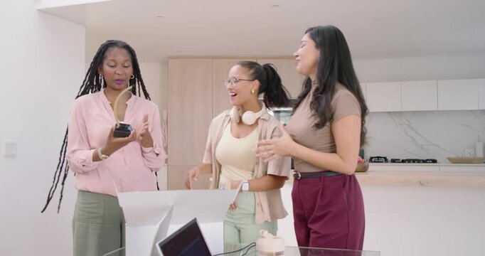 Diverse female friends unboxing trophy on table, posing for phone selfies in kitchen celebrating
