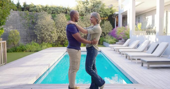 Couple initiating embrace, shifting and holding hands on wooden deck beside pool, sharing affection