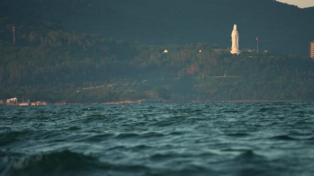 Lady Buddha statue and Linh Ung Pagoda above coastline with sea waves and mountains in Da Nang, Coastal landscape with ocean waves and Son Tra Peninsula, Danang Vietnam 4k