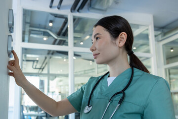 Fototapeta premium Dark-haired female doctor in lab coat setting the temperature range in a room