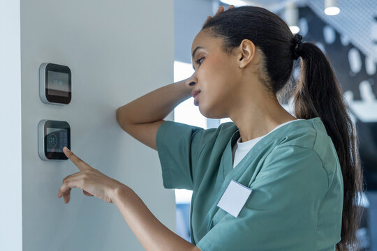 Tired after night shift doctor setting temperature on a climate control panel