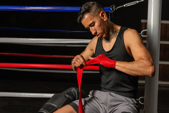young Hispanic boxer wrapping hands before training in gym