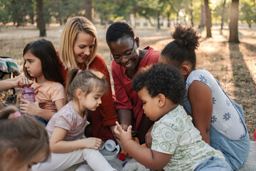 Obraz premium Teachers and preschool children playing together in the park