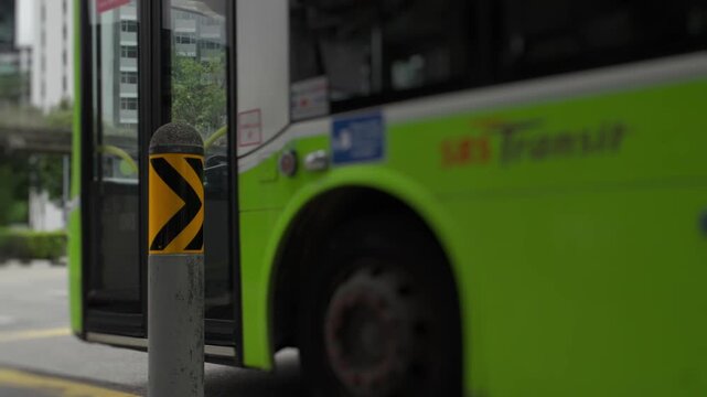Green public bus leaving station in singapore city