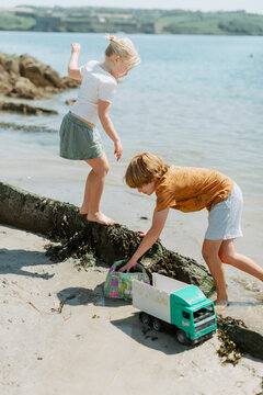 Children playing and exploring on a sandy beach during family vacation