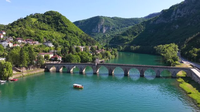 Visegrad, Bosnia and Herzegovina &ndash; May 30, 2026: Wide panoramic drone view of Mehmed Pasha Sokolovic Bridge surrounded by green mountains and the Drina River