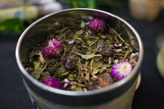 Close up of premium loose leaf tea blend with dried purple flowers in a tin