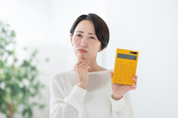 電卓を持って悩む女性