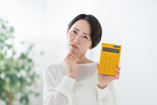 電卓を持って悩む女性