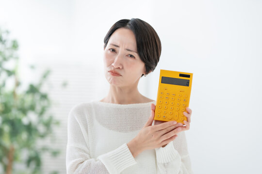 電卓を持って悩む女性