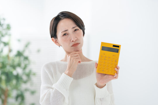 電卓を持って悩む女性