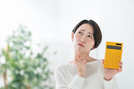 電卓を持って悩む女性