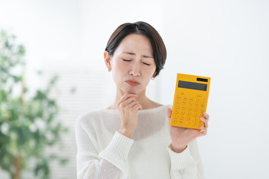 電卓を持って悩む女性