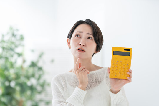 電卓を持って悩む女性