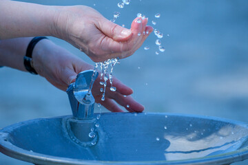 Refreshing water flows from a fountain into outstretched hands © aviavlad