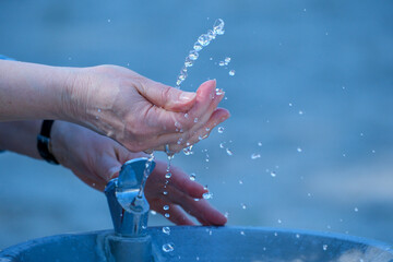 Fototapeta premium Hands playfully catching droplets from a fountain on a sunny day