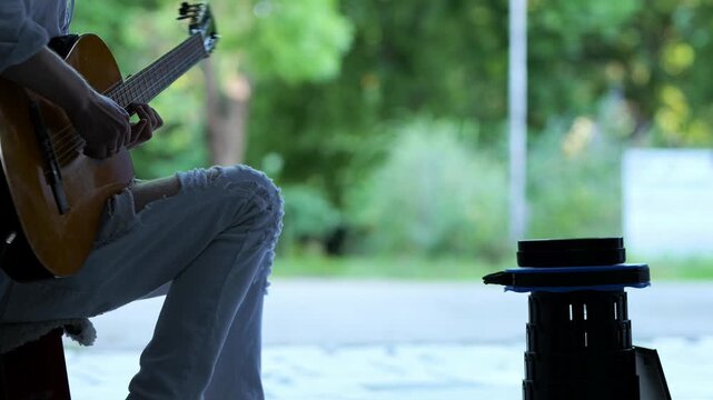 Street musician playing acoustic guitar in a public park