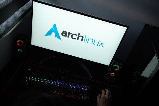 Punta Arenas, Chile &ndash; June 12, 2026: The official blue Arch Linux logo displayed on a computer screen in a dark workspace setup with an RGB backlit keyboard