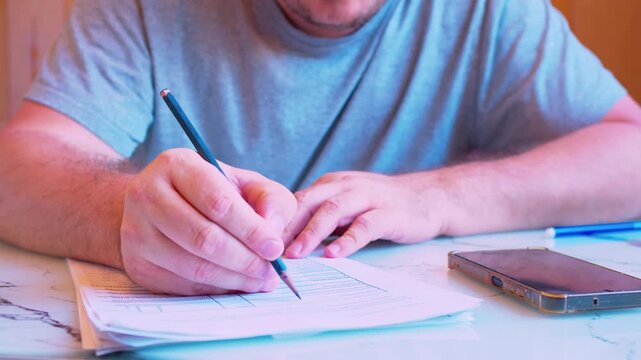 Cinematic shot of paper work  on documents on a desk at home. Defocused blurreed man, soft window light. Visualizes tax filing, family budget planning and household management.